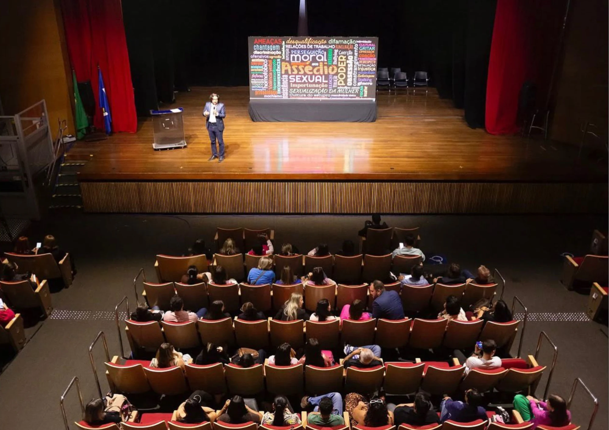 Vista do teatro com Douglas no palco e a plateia à frente