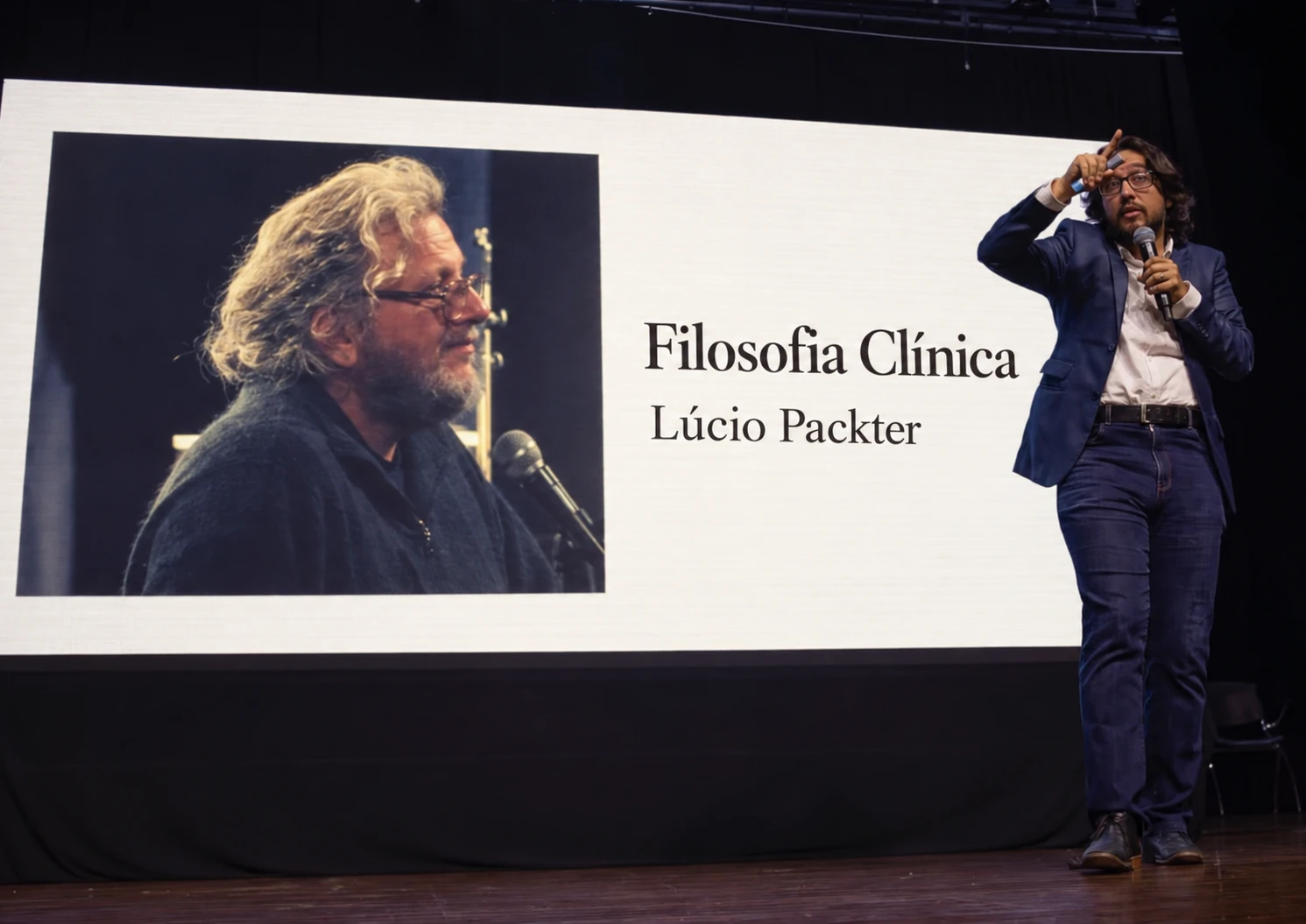 Douglas no palco com a imagem de Lúcio Packter e o título Filosofia Clínica no telão